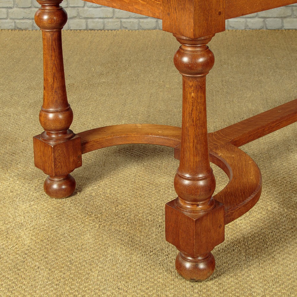 A long solid oak refectory dining table featuring turned legs and a low curved stretcher base. View X