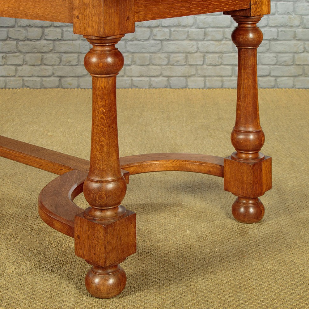 A long solid oak refectory dining table featuring turned legs and a low curved stretcher base. View XI