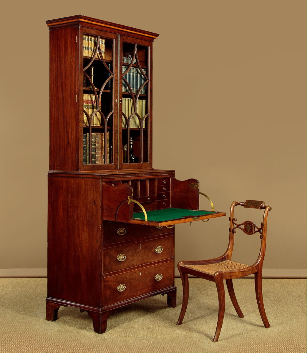 A tall mahogany secretaire bureau bookcase featuring two upper glazed doors with geometric astragal glazing over a chest of drawers with brass oval handles. View II