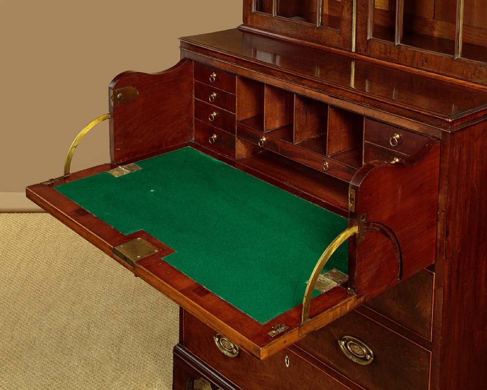 A tall mahogany secretaire bureau bookcase featuring two upper glazed doors with geometric astragal glazing over a chest of drawers with brass oval handles. View VIII