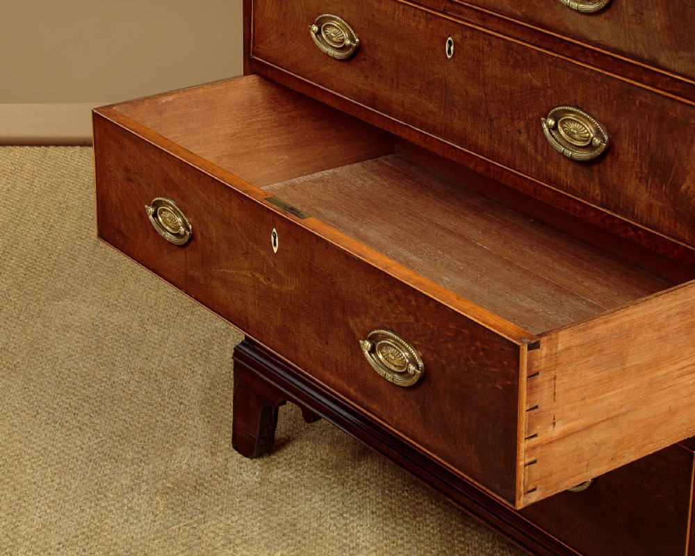 A tall mahogany secretaire bureau bookcase featuring two upper glazed doors with geometric astragal glazing over a chest of drawers with brass oval handles. View XIV