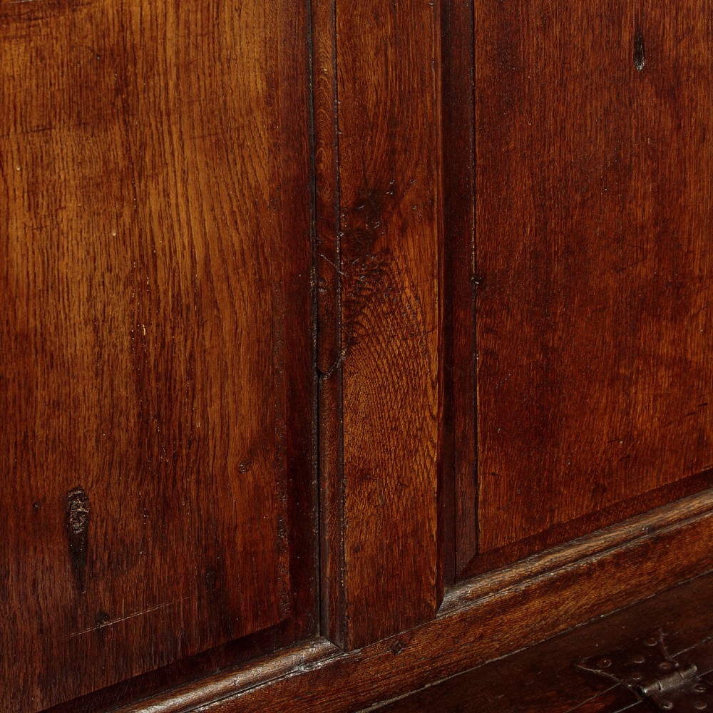 A dark oak 18th-century high-back box settle featuring fielded panels, shaped open armrests, and a hinged lid seat. View IX