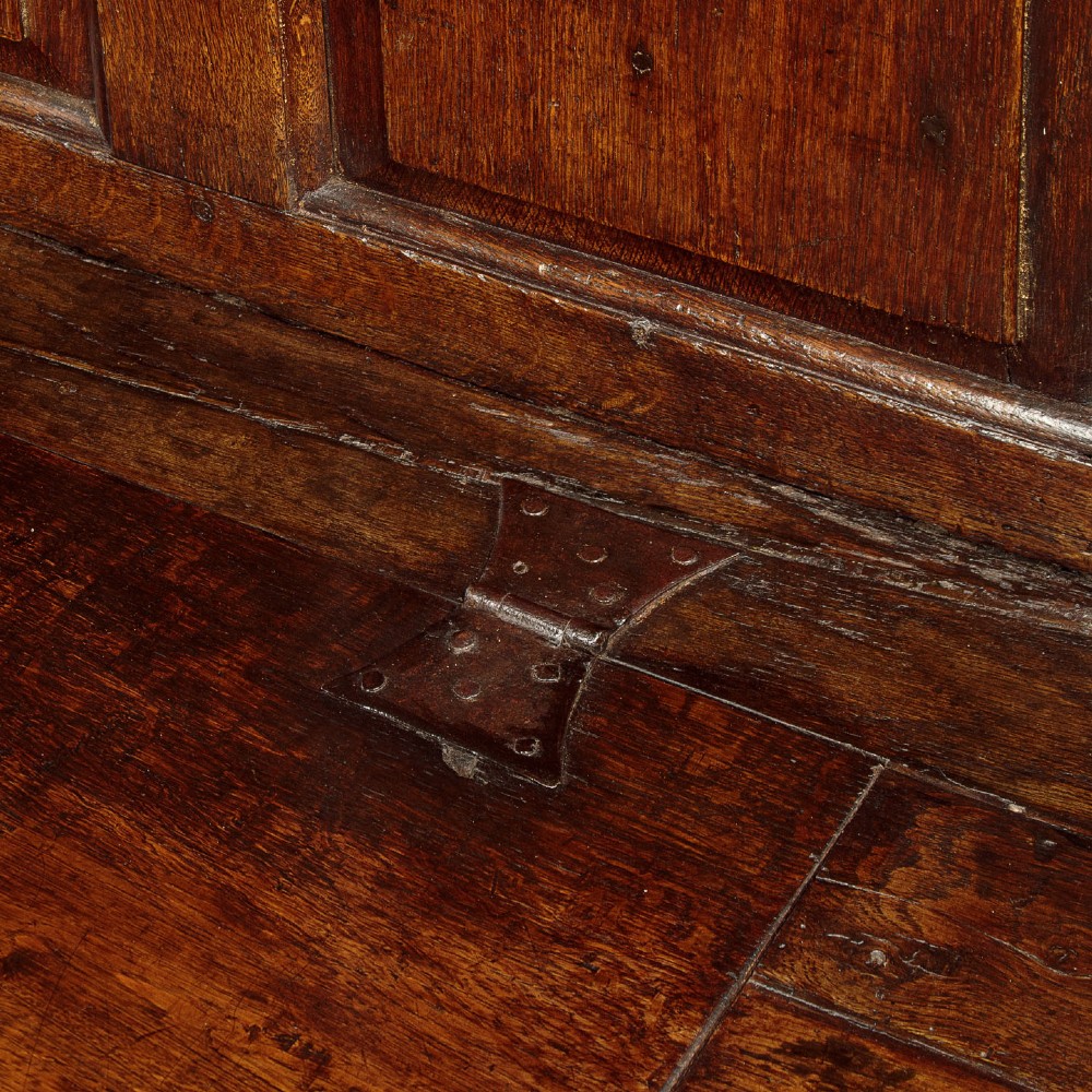 A dark oak 18th-century high-back box settle featuring fielded panels, shaped open armrests, and a hinged lid seat. View X