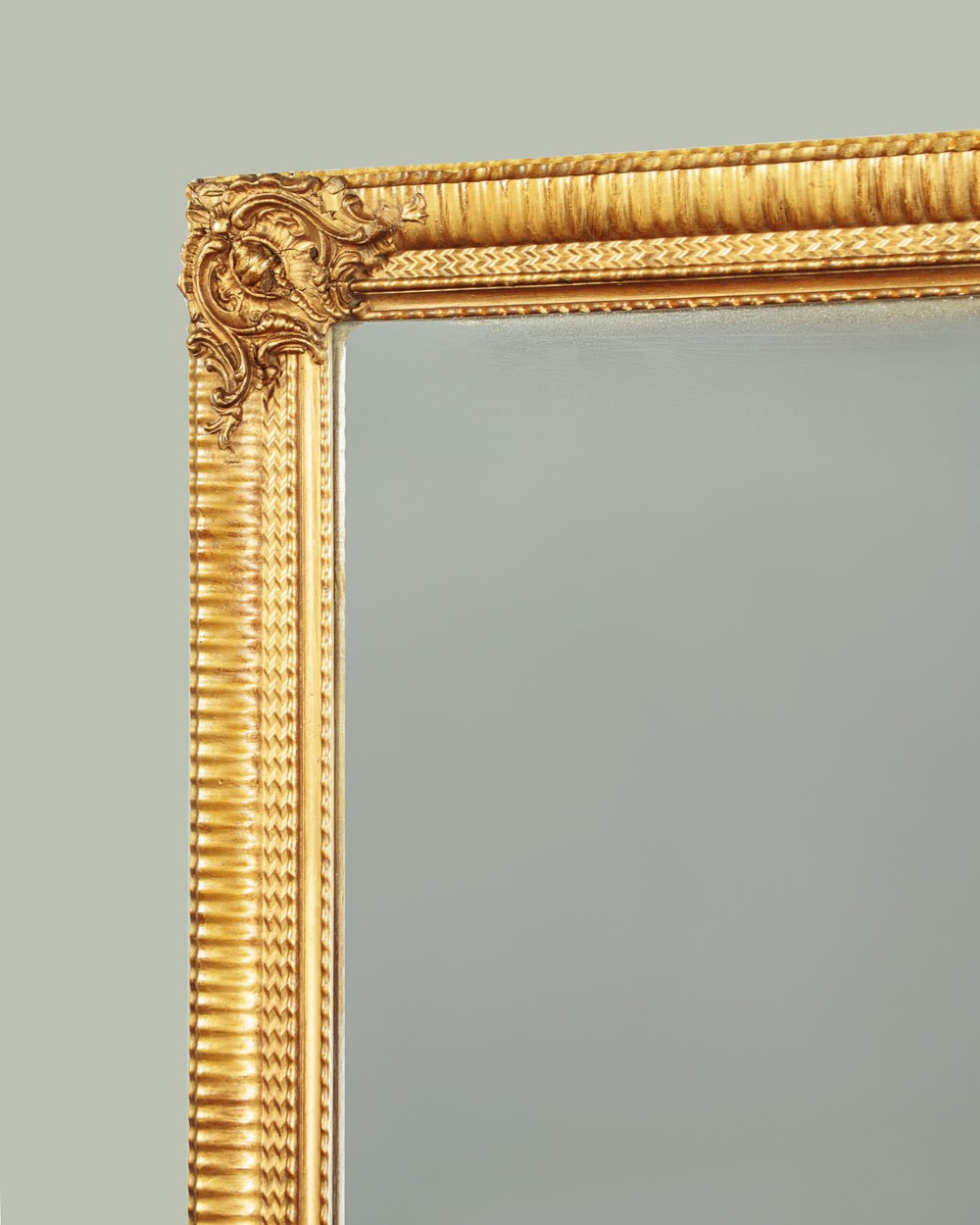 A rectangular wall mirror featuring a gilded frame with reeded moulding and carved scrollwork details in each corner. View IV