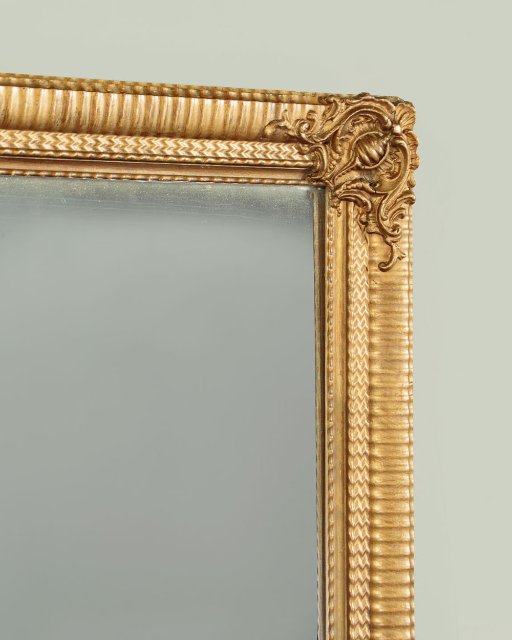 A rectangular wall mirror featuring a gilded frame with reeded moulding and carved scrollwork details in each corner. View V