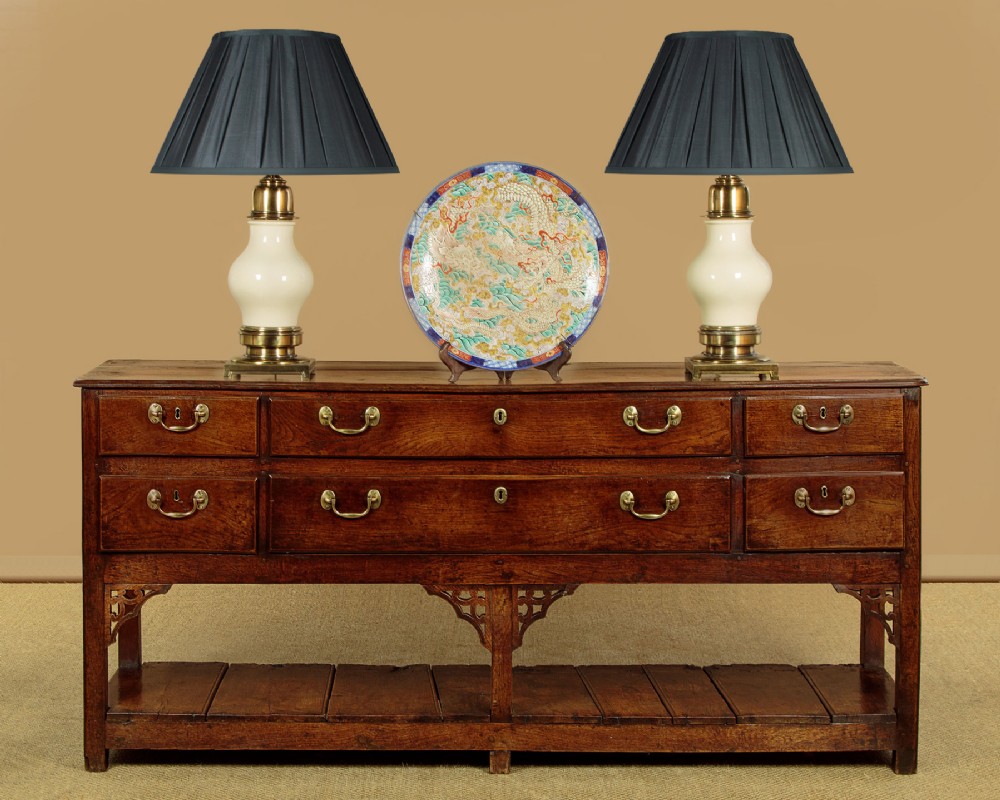 A eighteenth-century Georgian dark oak potboard dresser base featuring six drawer fronts with brass swan-neck handles and an open lower shelf. View II