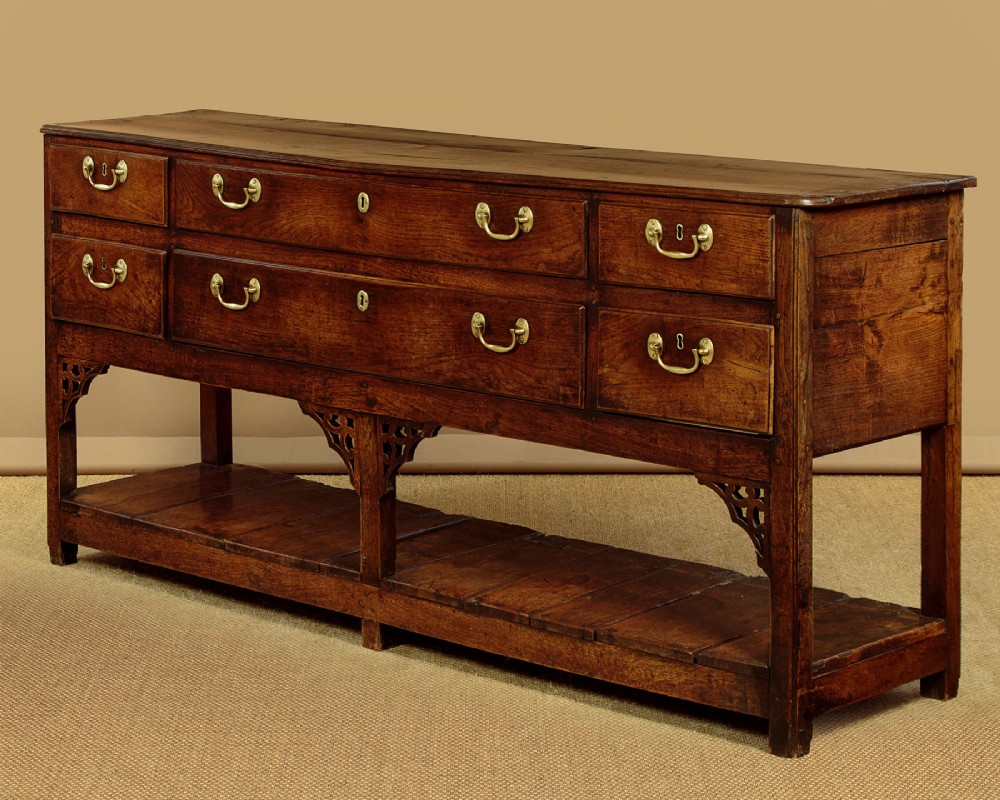 A eighteenth-century Georgian dark oak potboard dresser base featuring six drawer fronts with brass swan-neck handles and an open lower shelf. View III