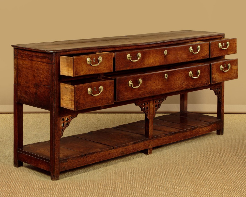 A eighteenth-century Georgian dark oak potboard dresser base featuring six drawer fronts with brass swan-neck handles and an open lower shelf. View IV