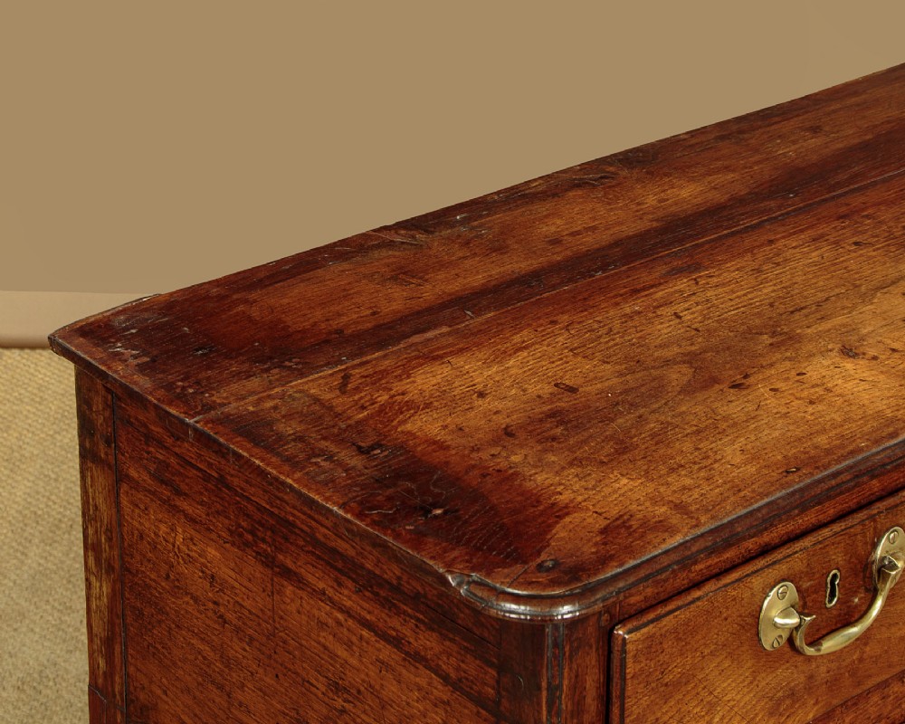 A eighteenth-century Georgian dark oak potboard dresser base featuring six drawer fronts with brass swan-neck handles and an open lower shelf. View VII
