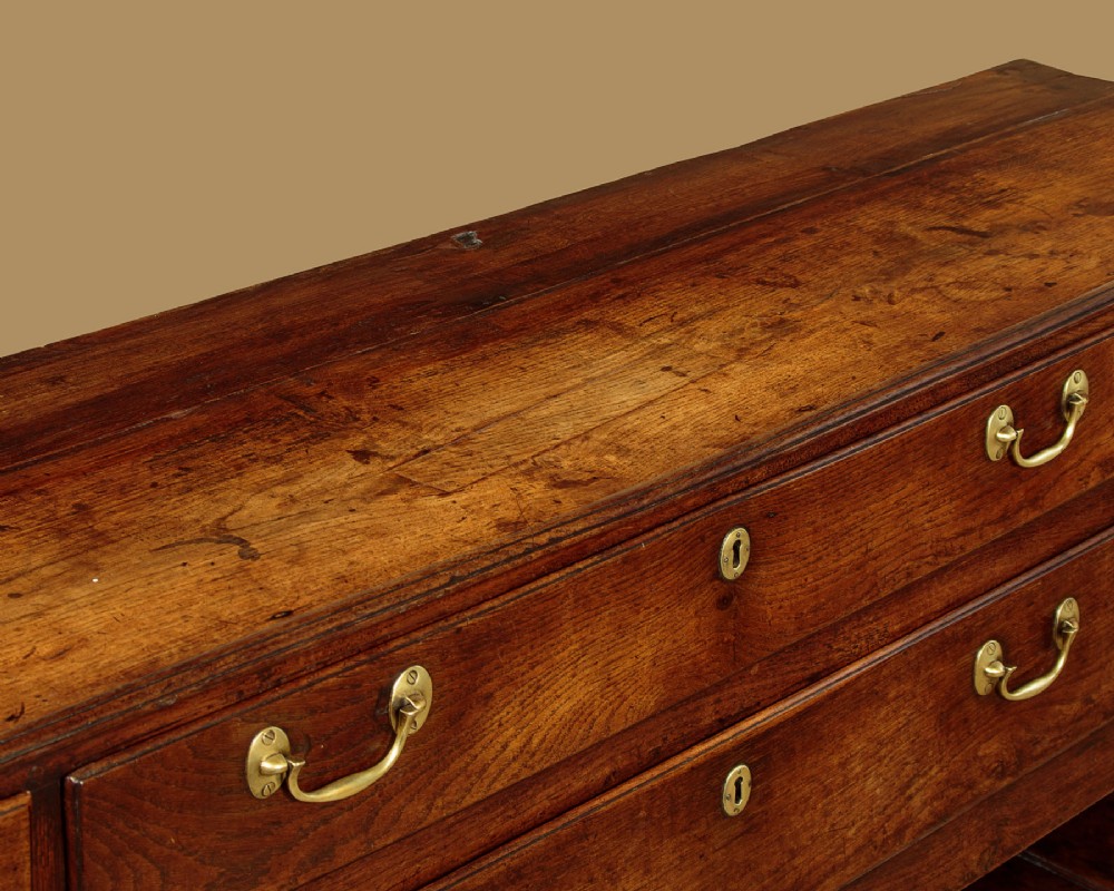 A eighteenth-century Georgian dark oak potboard dresser base featuring six drawer fronts with brass swan-neck handles and an open lower shelf. View VIII