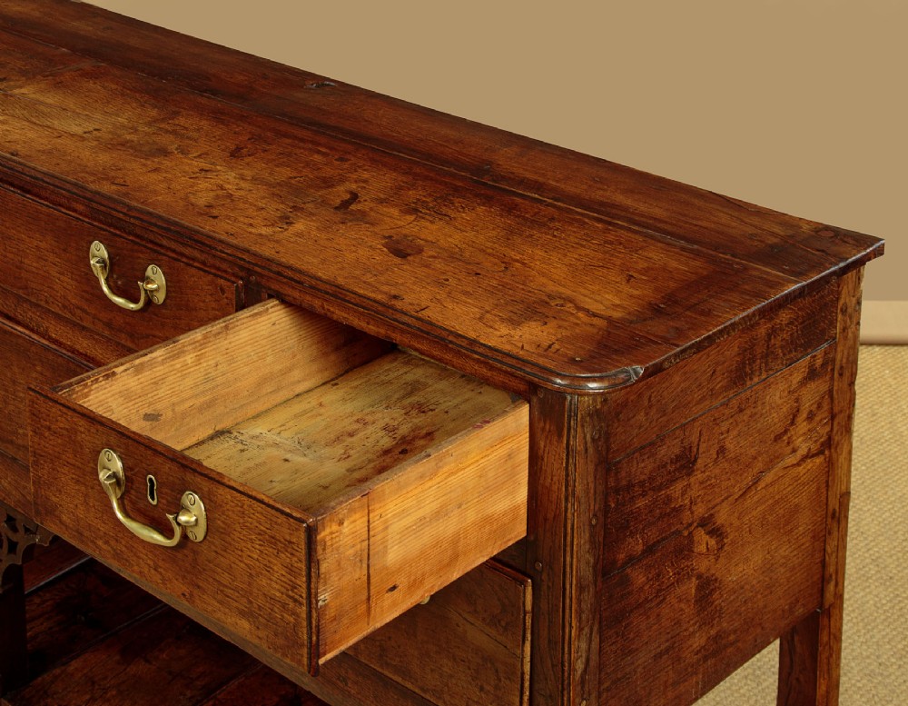 A eighteenth-century Georgian dark oak potboard dresser base featuring six drawer fronts with brass swan-neck handles and an open lower shelf. View IX