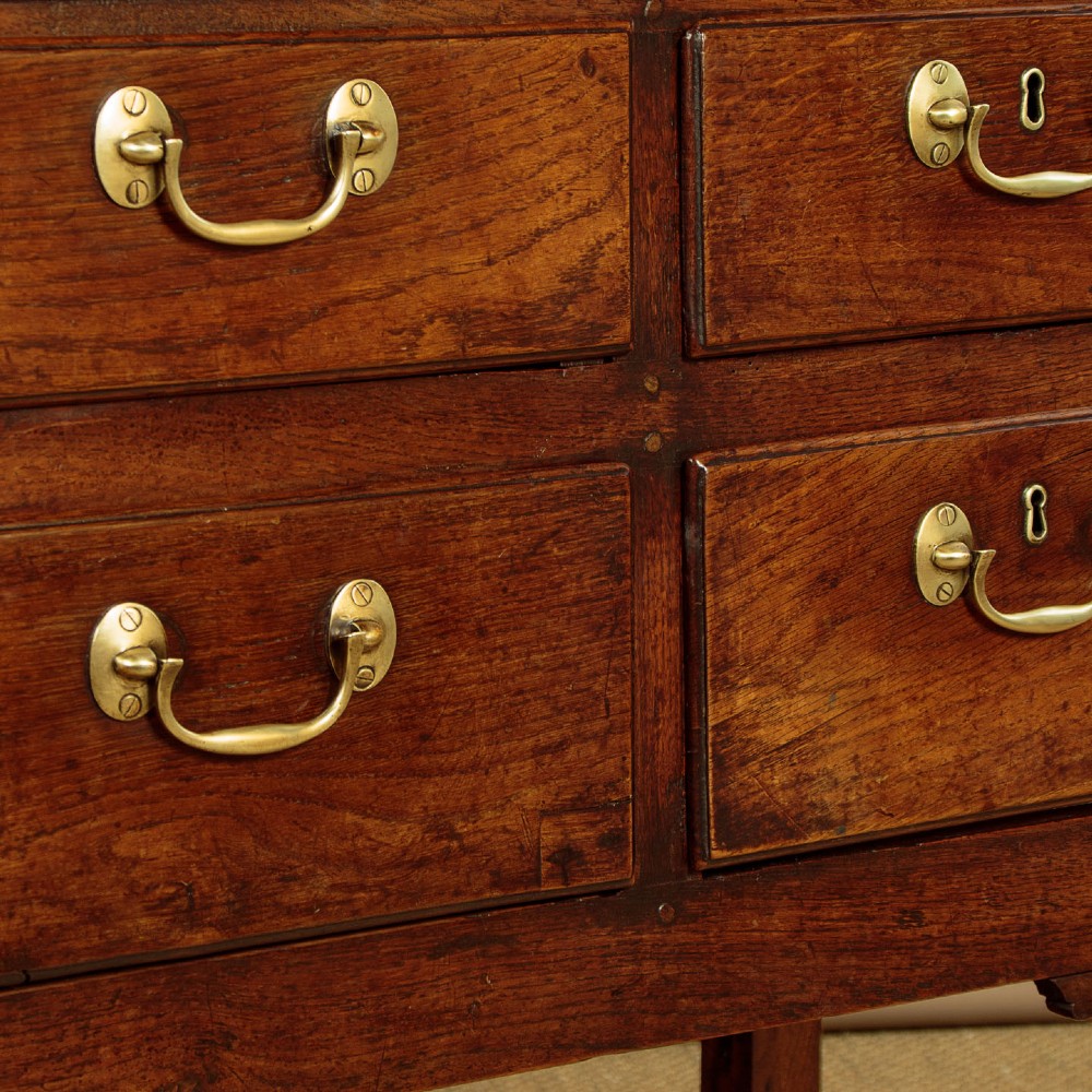 A eighteenth-century Georgian dark oak potboard dresser base featuring six drawer fronts with brass swan-neck handles and an open lower shelf. View XI