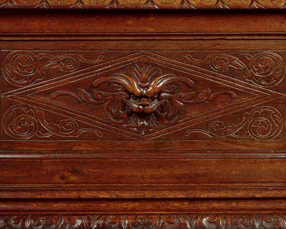 A long late Victorian dark oak ottoman box seat featuring an inset leather top with brass studding, carved relief mask panels, and a heavy moulded base. View VII