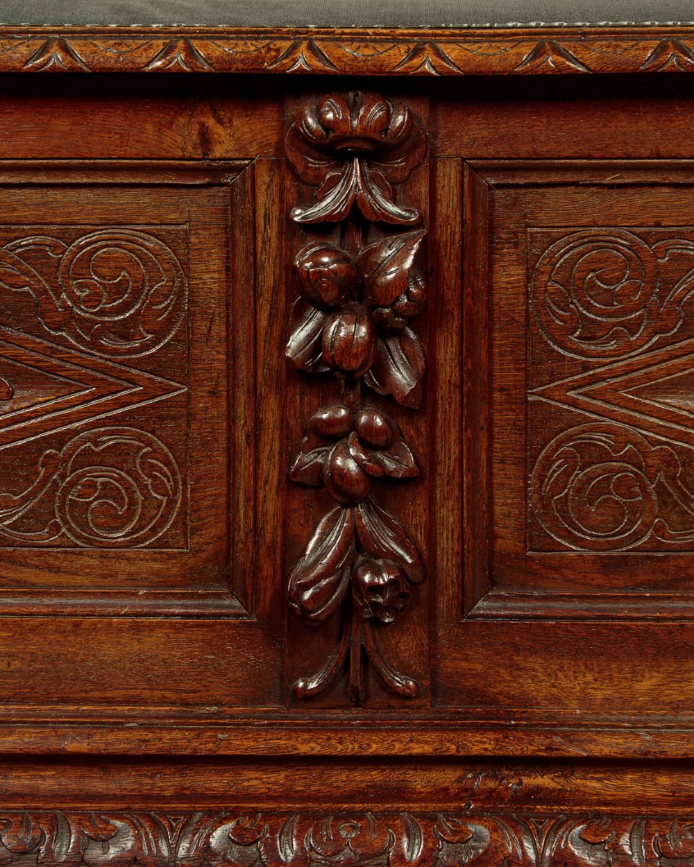 A long late Victorian dark oak ottoman box seat featuring an inset leather top with brass studding, carved relief mask panels, and a heavy moulded base. View VIII
