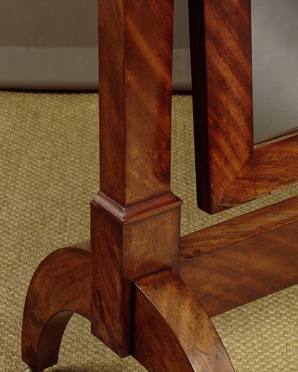 A mid-19th-century mahogany cheval mirror featuring a rectangular swivelling frame set between upright supports with an architectural corniced top and brass mount, resting on splayed feet with castors. View V