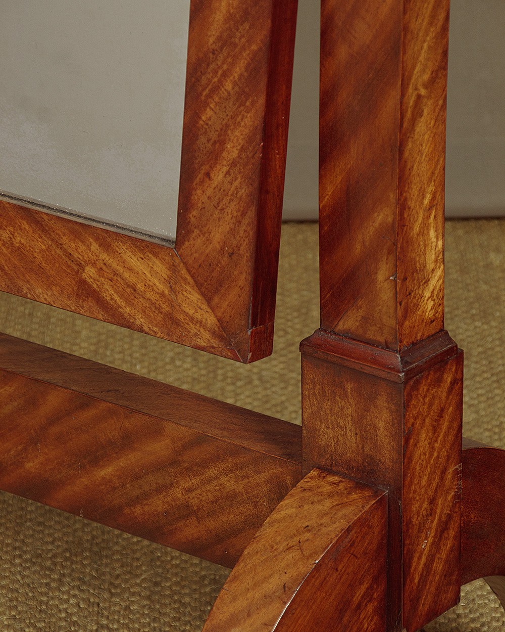 A mid-19th-century mahogany cheval mirror featuring a rectangular swivelling frame set between upright supports with an architectural corniced top and brass mount, resting on splayed feet with castors. View VI