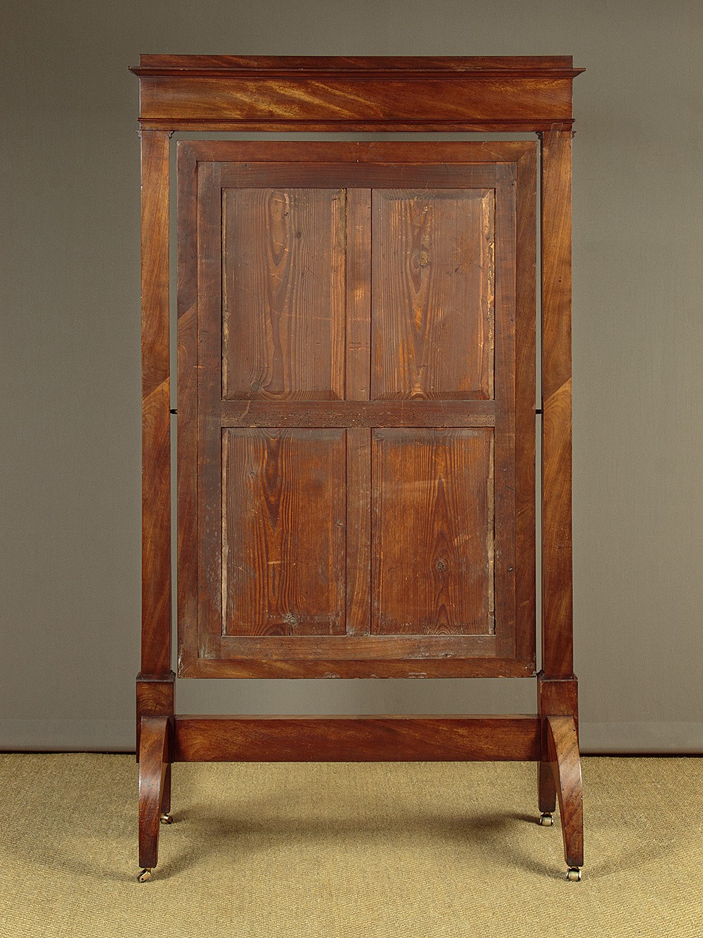 A mid-19th-century mahogany cheval mirror featuring a rectangular swivelling frame set between upright supports with an architectural corniced top and brass mount, resting on splayed feet with castors. View VIII