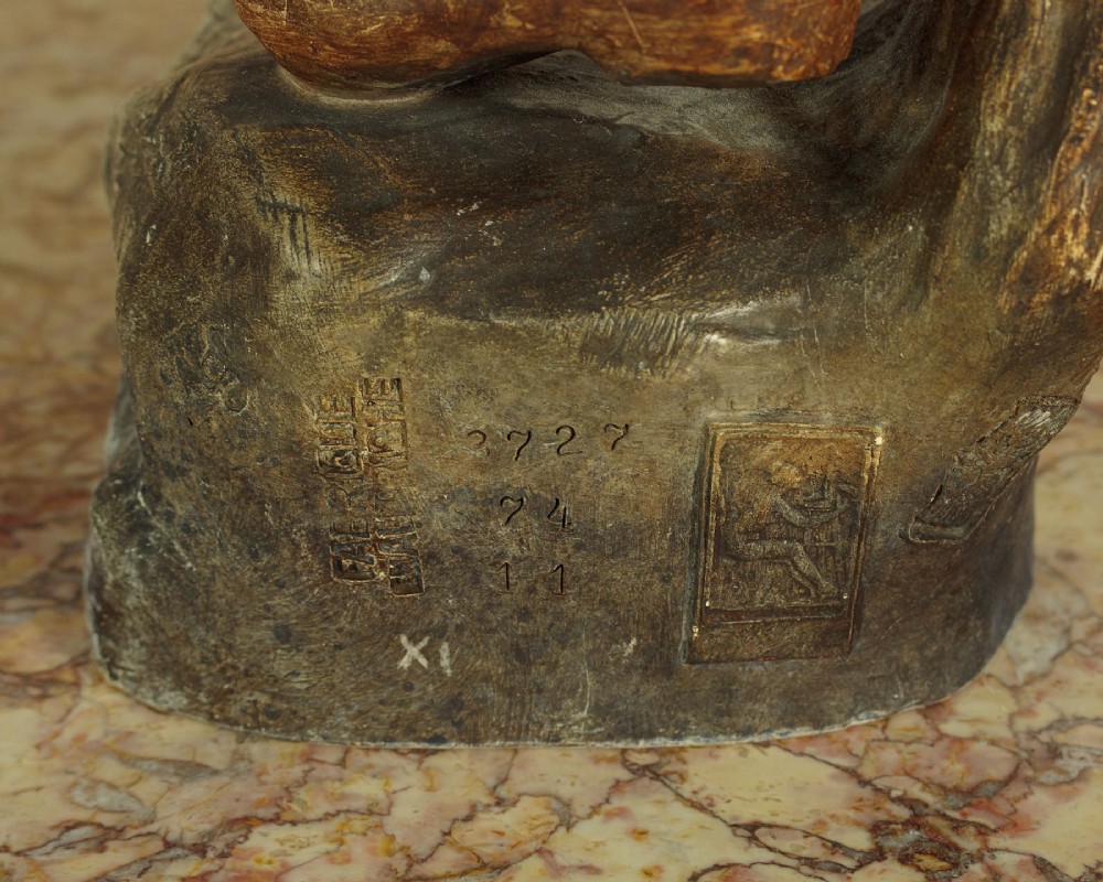 A turn-of-the-century terracotta sculpture depicting a standing young woman in rural dress wearing a headscarf and clogs, holding a basket. View X