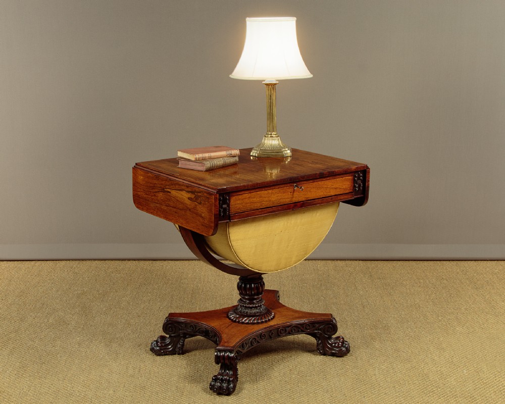 A nineteenth-century rosewood Pembroke side table with drop-leaf sides, a fabric work basket, turned column, and carved scroll feet. View II