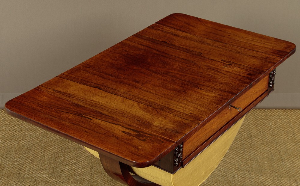 A nineteenth-century rosewood Pembroke side table with drop-leaf sides, a fabric work basket, turned column, and carved scroll feet. View IV