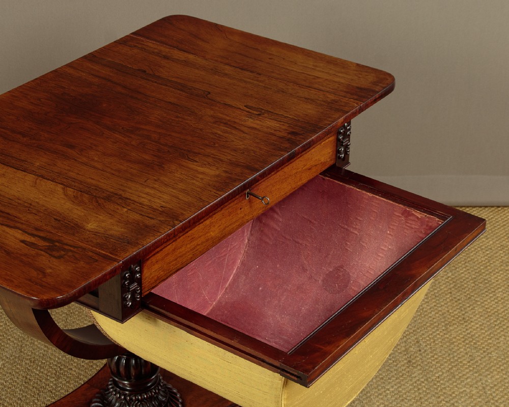 A nineteenth-century rosewood Pembroke side table with drop-leaf sides, a fabric work basket, turned column, and carved scroll feet. View VI