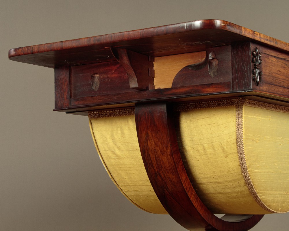 A nineteenth-century rosewood Pembroke side table with drop-leaf sides, a fabric work basket, turned column, and carved scroll feet. View VII