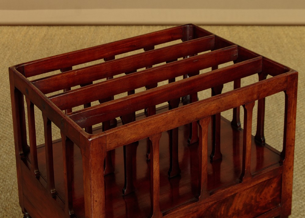 A dark mahogany Canterbury featuring four open slatted dividers above a single drawer with turned legs and brass castors. View V