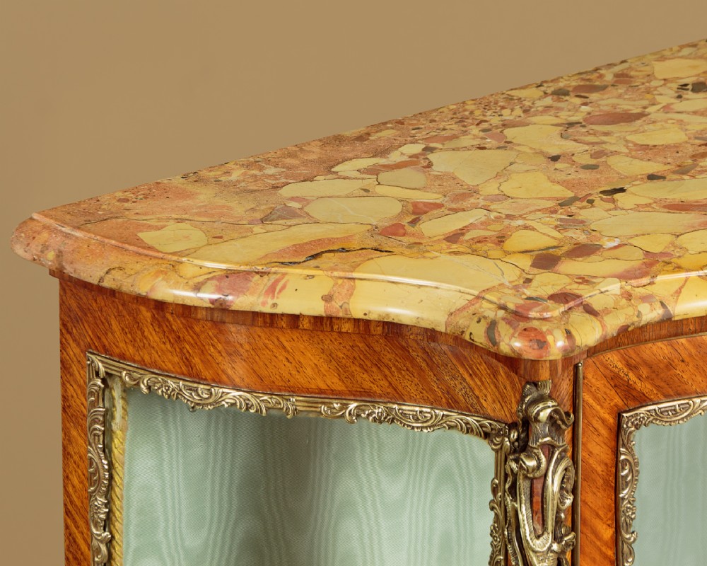 A small French Louis XV style vitrine with curved glass sides, a single glazed door, gilded brass mounts, a marble top, and a pale green fabric-lined interior with glass shelves. View VI
