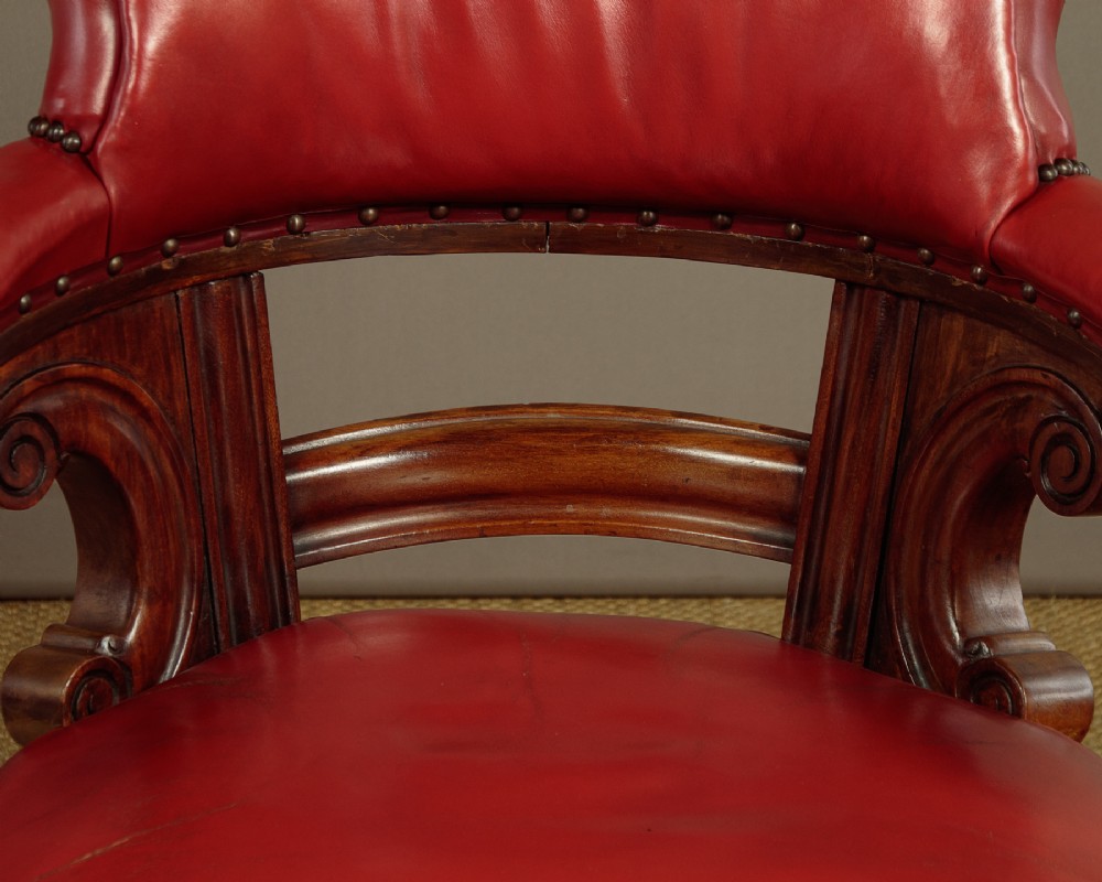A pair of late Victorian walnut tub armchairs with red leather upholstery, studded brass trim, turned front legs, and carved scroll arm supports. View VII