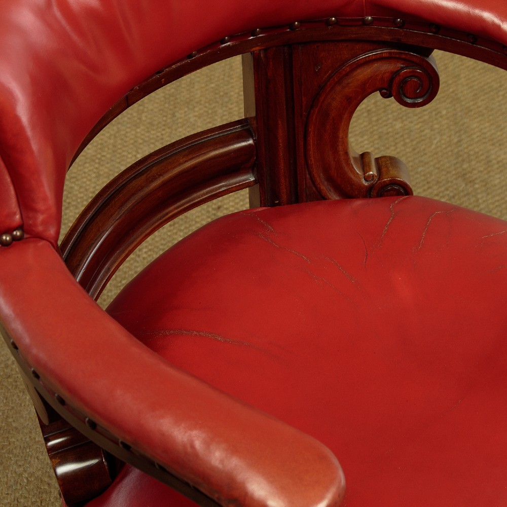 A pair of late Victorian walnut tub armchairs with red leather upholstery, studded brass trim, turned front legs, and carved scroll arm supports. View VIII