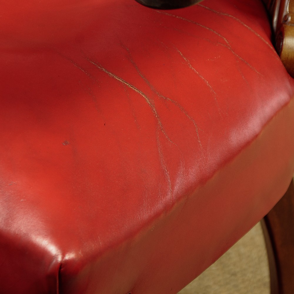 A pair of late Victorian walnut tub armchairs with red leather upholstery, studded brass trim, turned front legs, and carved scroll arm supports. View IX
