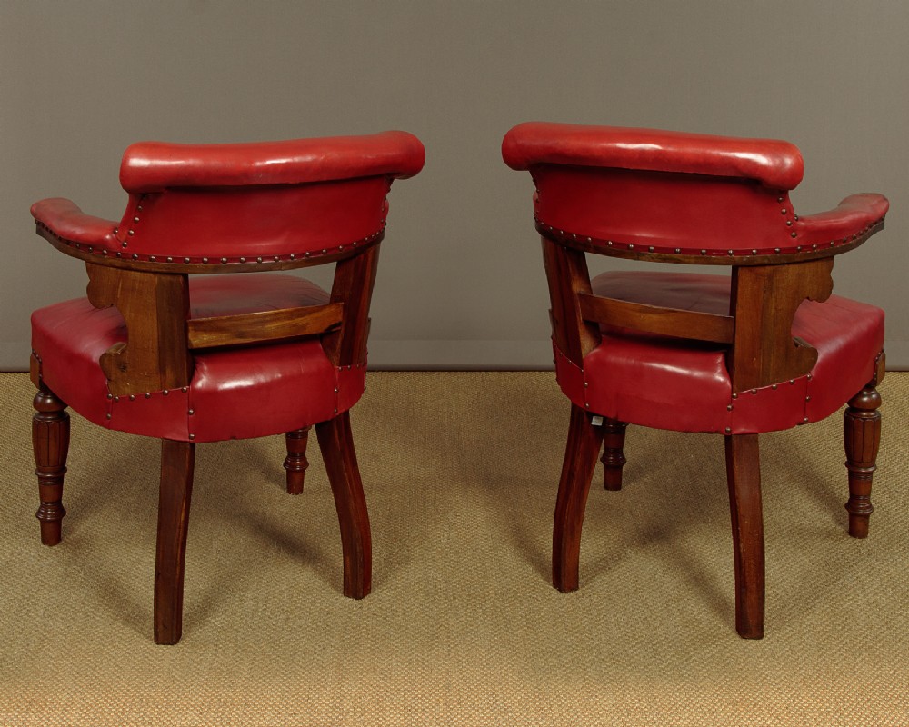 A pair of late Victorian walnut tub armchairs with red leather upholstery, studded brass trim, turned front legs, and carved scroll arm supports. View XII