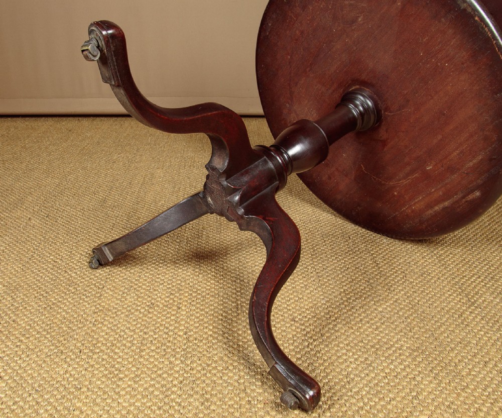 A two-tiered Georgian mahogany dumb waiter with turned baluster columns and a tripod base on brass castors. View X