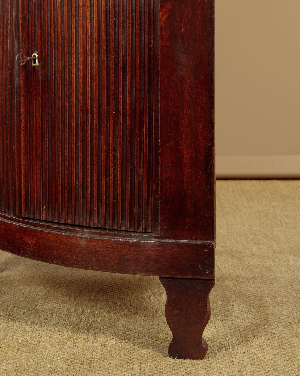 A tall early 19th-century dark mahogany double height corner cupboard featuring reeded front doors, a central drawer, and Gothic arcading at the cornice. View X