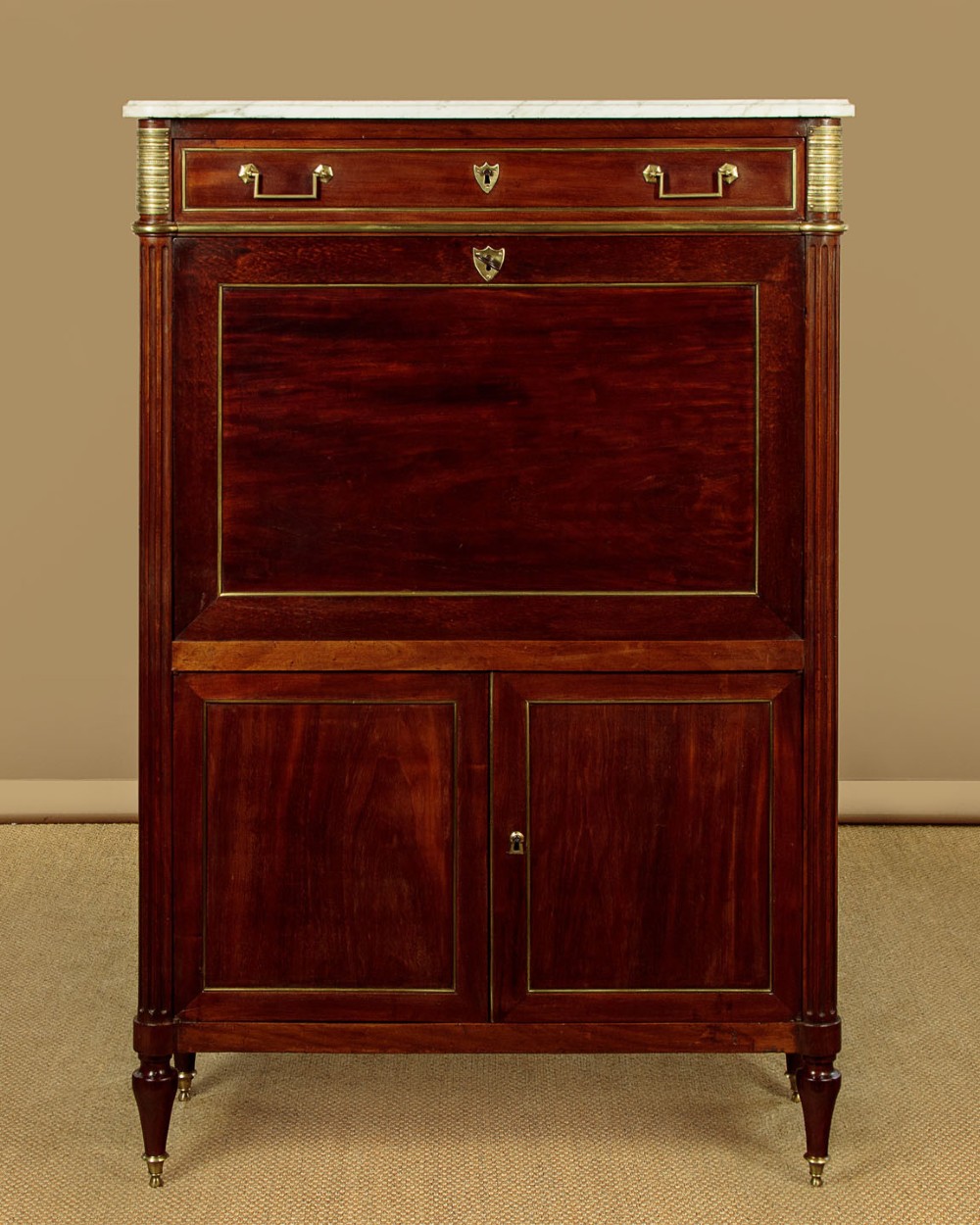 An 1830 mahogany secretaire abattant featuring a white marble top, brass-mounted fluted side columns, a drop-front writing panel, and a double-door cupboard.