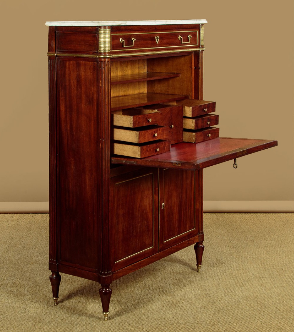 An 1830 mahogany secretaire abattant featuring a white marble top, brass-mounted fluted side columns, a drop-front writing panel, and a double-door cupboard. View VI