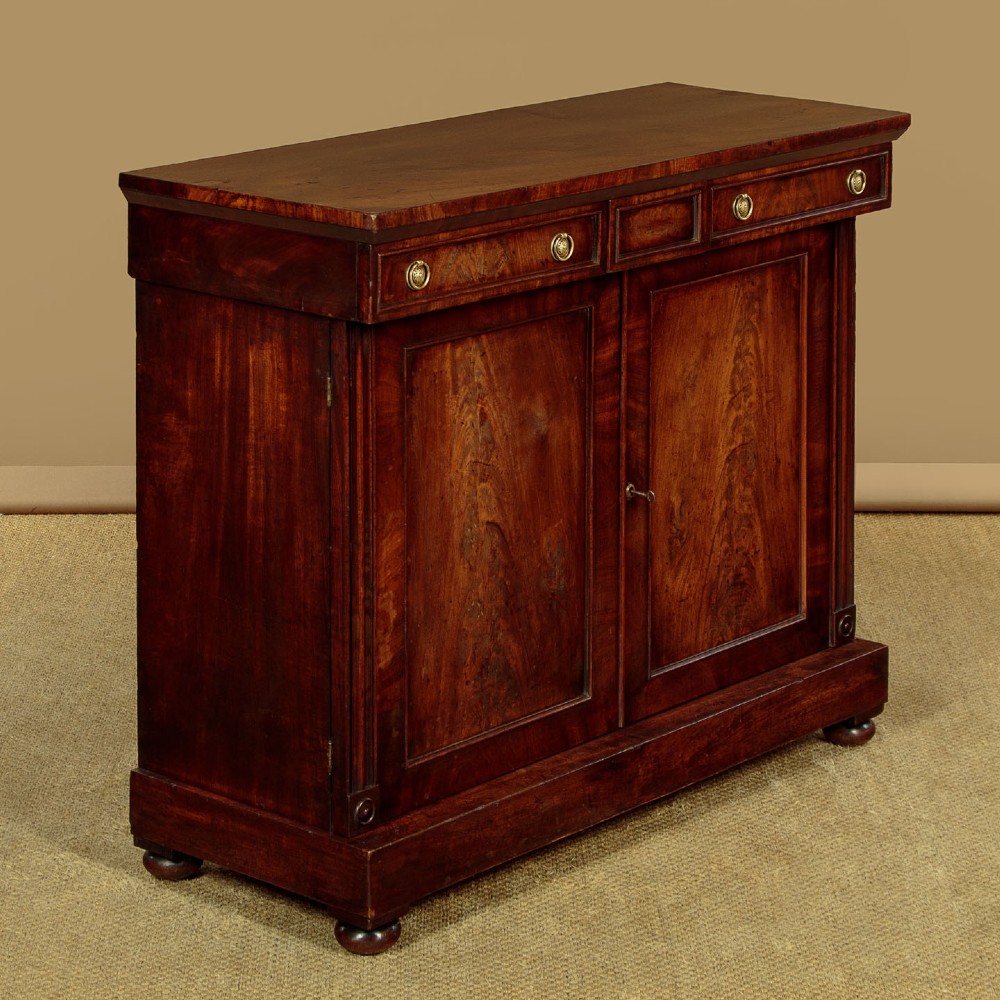 A Victorian flame mahogany chiffonier cabinet featuring frieze drawers with brass ring pulls and twin panelled cupboard doors on a plinth base. View II