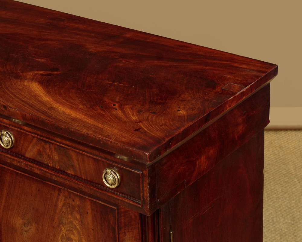 A Victorian flame mahogany chiffonier cabinet featuring frieze drawers with brass ring pulls and twin panelled cupboard doors on a plinth base. View VI