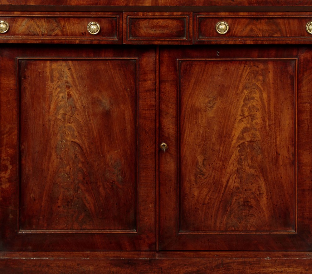 A Victorian flame mahogany chiffonier cabinet featuring frieze drawers with brass ring pulls and twin panelled cupboard doors on a plinth base. View IX
