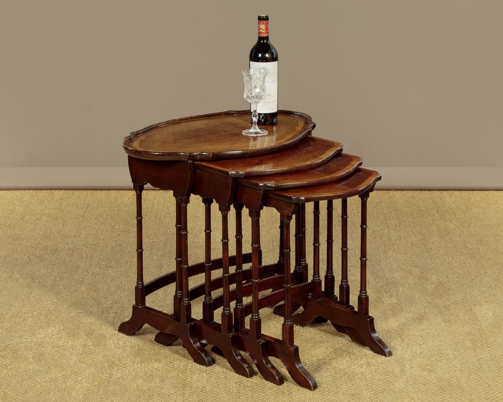 A set of four graduated dark mahogany quartetto nesting tables featuring turned spindle legs and shaped tops. View II