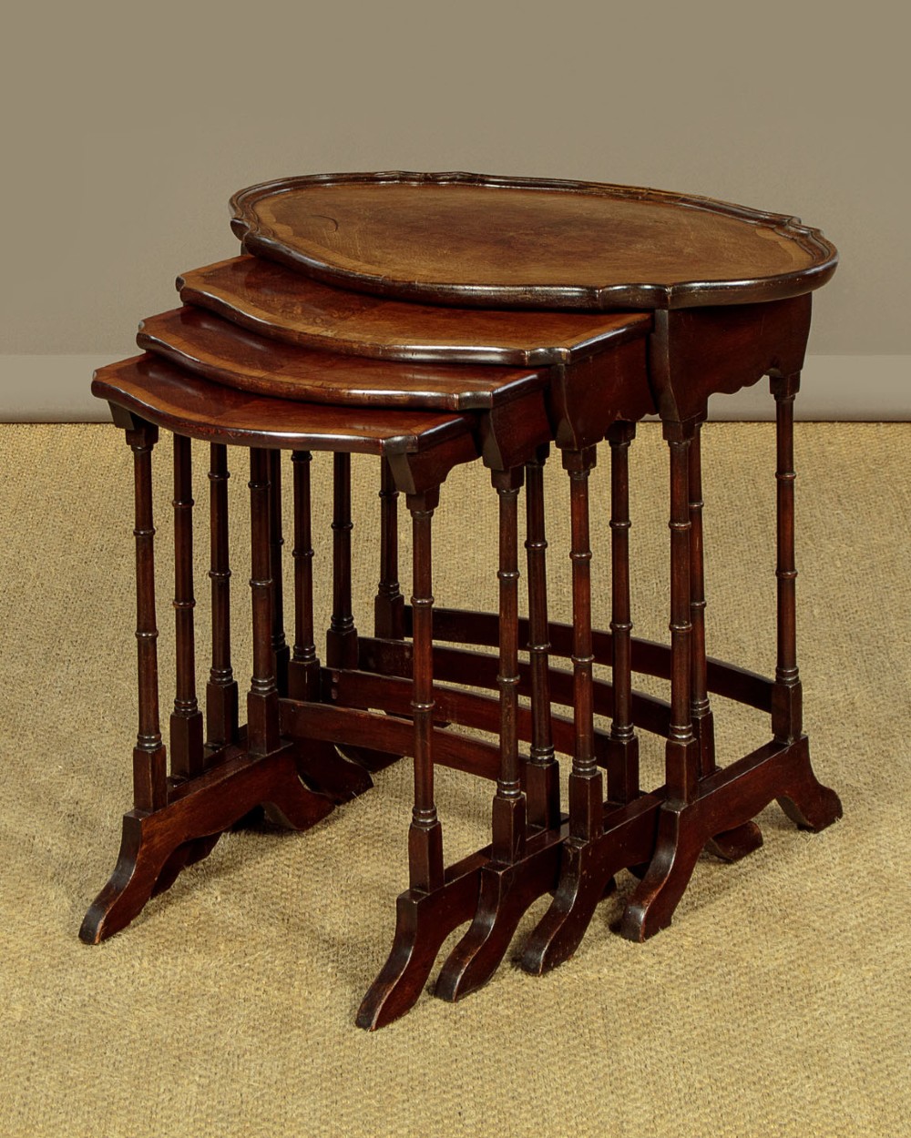 A set of four graduated dark mahogany quartetto nesting tables featuring turned spindle legs and shaped tops. View III