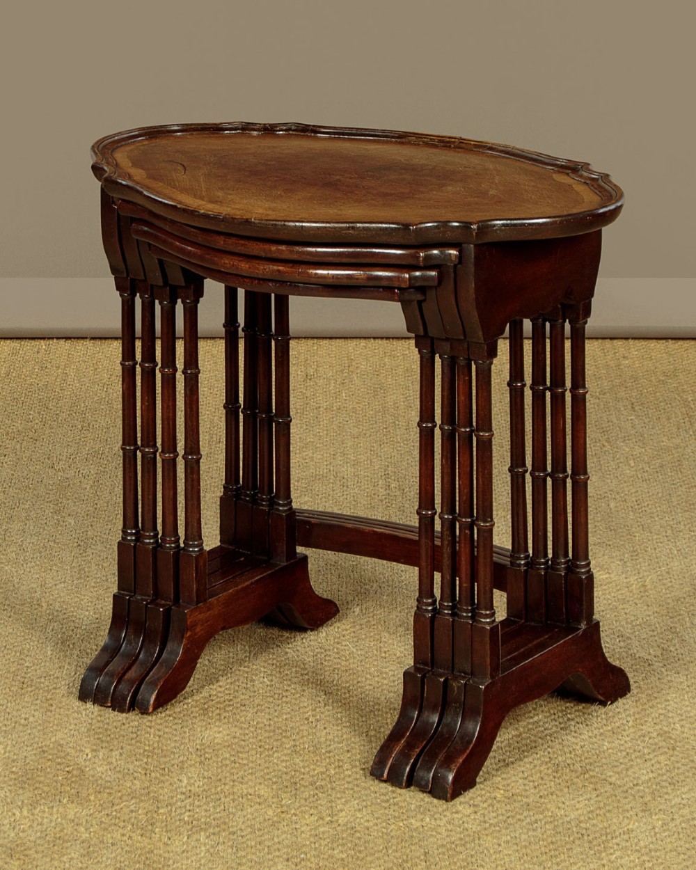 A set of four graduated dark mahogany quartetto nesting tables featuring turned spindle legs and shaped tops. View IV