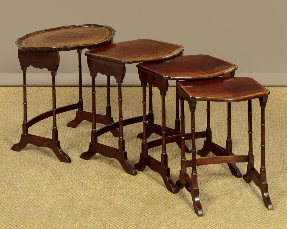 A set of four graduated dark mahogany quartetto nesting tables featuring turned spindle legs and shaped tops. View V