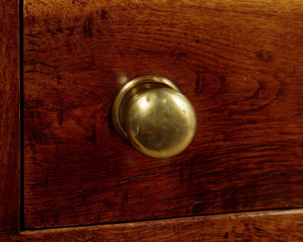 An 18th-century oak dresser base featuring three drawers with brass knobs, a scalloped lower apron, and four straight legs. View VIII