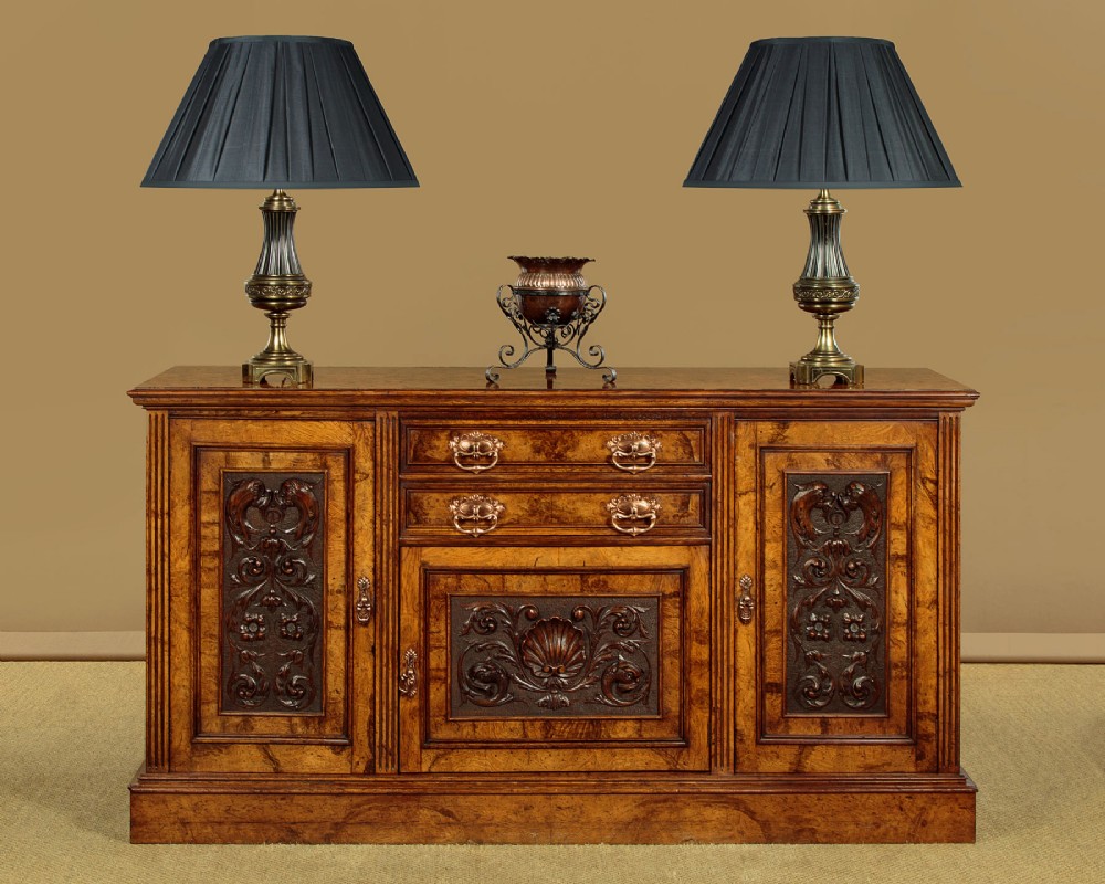 A late Victorian pollard oak sideboard featuring relief-carved panel doors, two central drawers with brass handles, and a continuous plinth base. View II