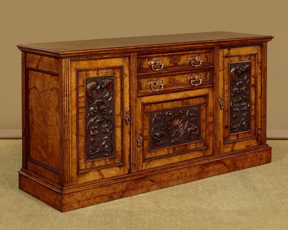 A late Victorian pollard oak sideboard featuring relief-carved panel doors, two central drawers with brass handles, and a continuous plinth base. View III