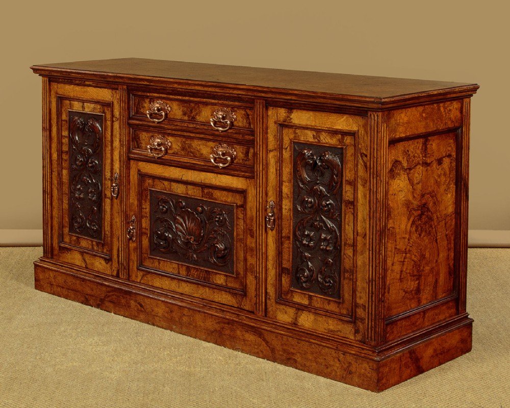 A late Victorian pollard oak sideboard featuring relief-carved panel doors, two central drawers with brass handles, and a continuous plinth base. View IV