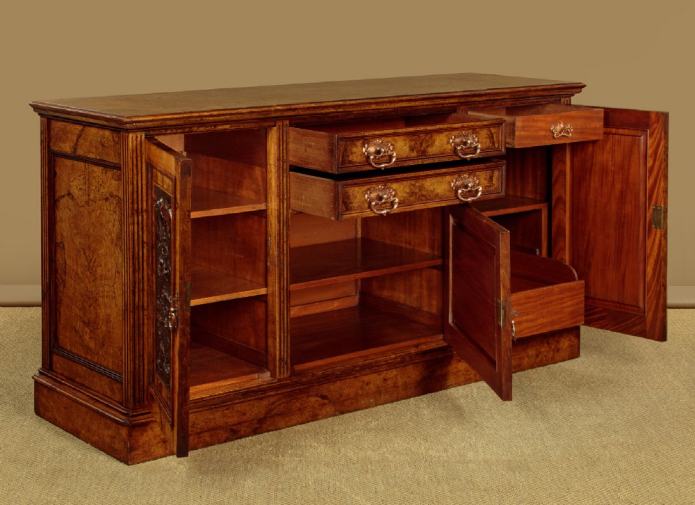 A late Victorian pollard oak sideboard featuring relief-carved panel doors, two central drawers with brass handles, and a continuous plinth base. View V