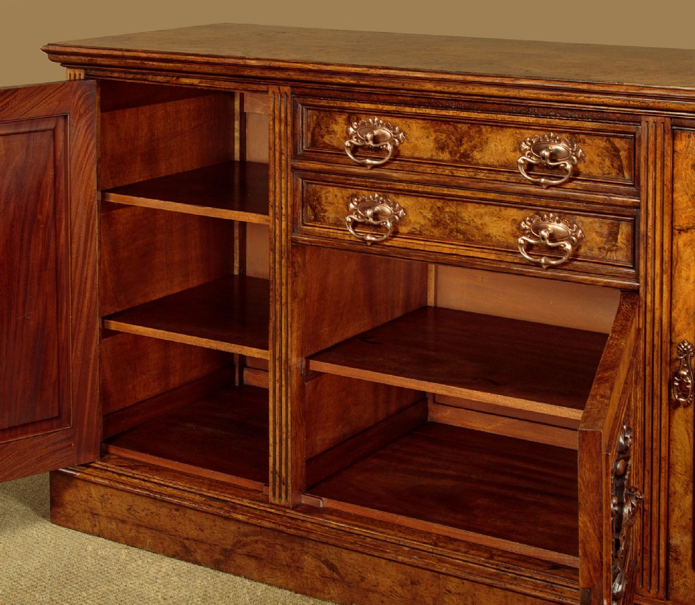 A late Victorian pollard oak sideboard featuring relief-carved panel doors, two central drawers with brass handles, and a continuous plinth base. View IX