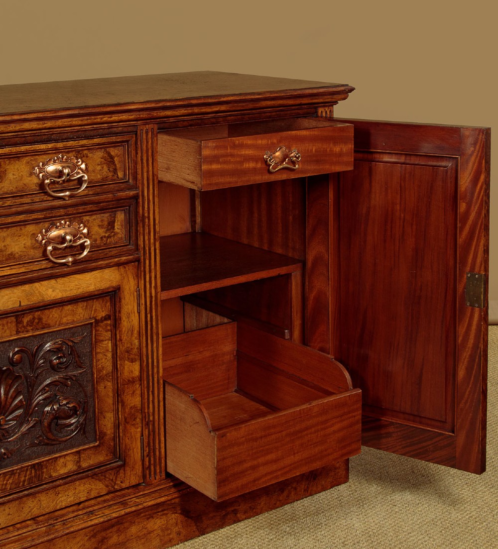 A late Victorian pollard oak sideboard featuring relief-carved panel doors, two central drawers with brass handles, and a continuous plinth base. View X